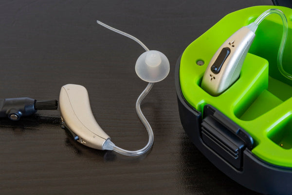 Hearing aids with their storage case and a cleaning brush.