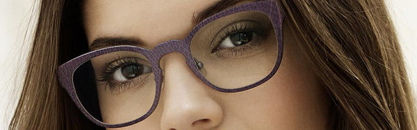 Close-up of a person wearing textured purple eyeglasses with clear lenses.