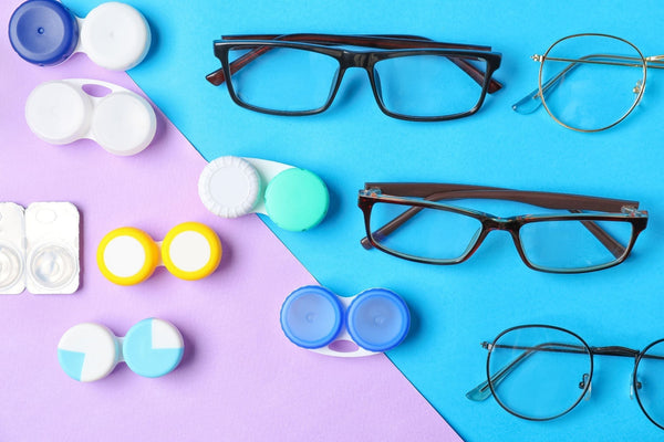 Various eyeglasses and multiple colorful contact lens cases arranged on a blue and purple background.