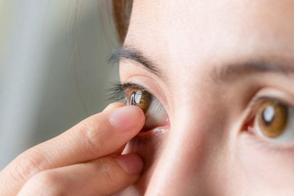 Close-up of a person gently inserting a contact lens into their eye, focusing on eye care and vision correction.