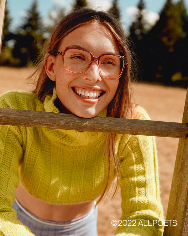woman in a field on a sunny day, wearing designer glasses