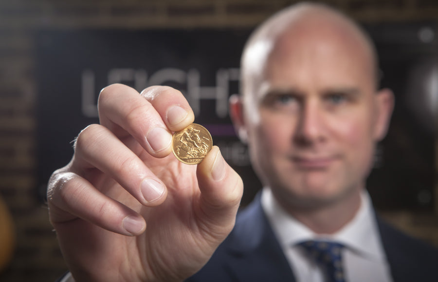 A woman with curly hair wearing glasses, standing in sunlight.