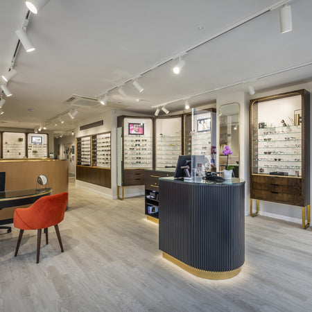 Optometry office interior with reception desk, chairs, and display cases.