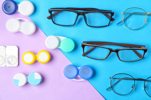 Various eyeglasses and multiple colorful contact lens cases arranged on a blue and purple background.