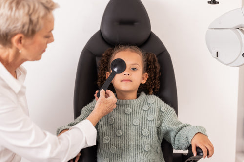 girl having her eye test with optical instrument in front of her right eye