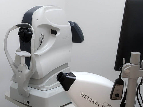 Ophthalmological examination room with eye examination equipment and chairs.