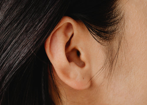 Close-up of a person's ear with dark hair partially covering it