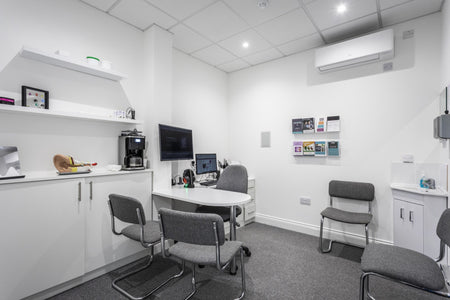 Modern office or meeting room with white walls, gray chairs, and a small table.