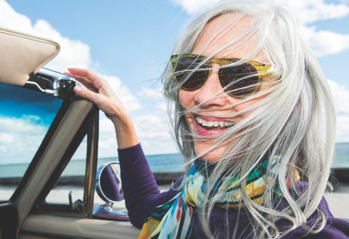 Woman with sunglasses and open car window by the sea