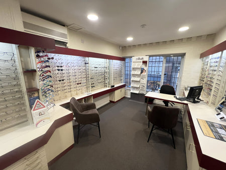 Optometrist office with shelves displaying eyeglasses and a reception desk.