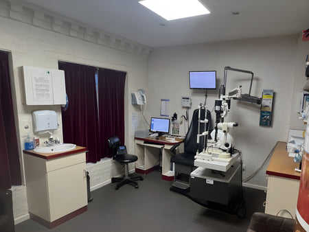 Medical examination room with eye examination equipment and computer monitors.