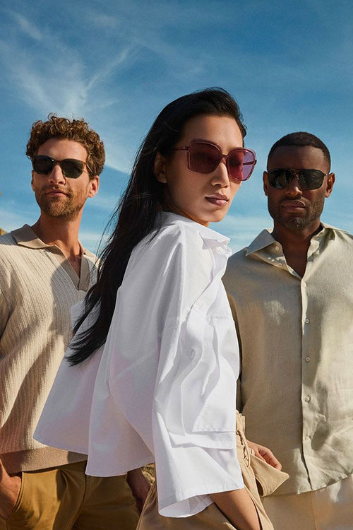 A smiling woman in a striped suit sits in a grey chair.