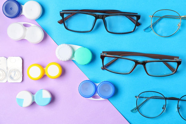 Various eyeglasses and multiple colorful contact lens cases arranged on a blue and purple background.