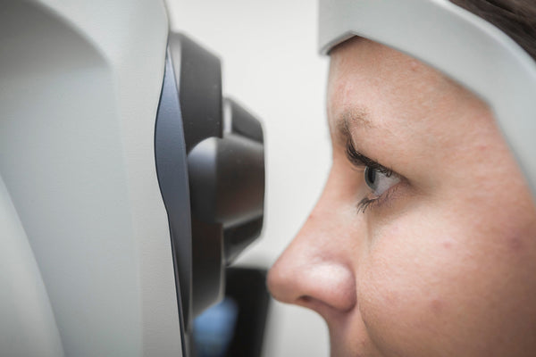 Person undergoing an eye examination using a digital eye testing device in a clinical setting.