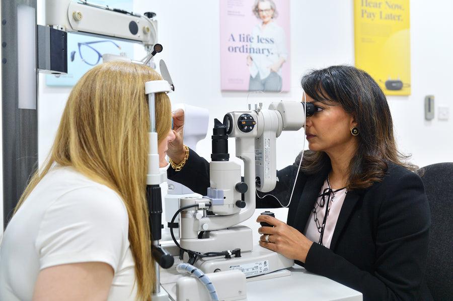 A hand holds a tablet displaying a retinal image with visible blood vessels.