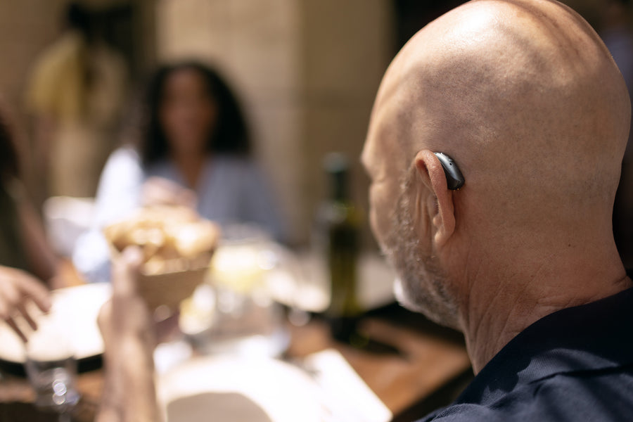A woman with braided hair smiles while wearing sunglasses on the beach.