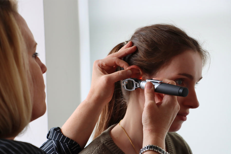 A woman with dark hair styled in a half-updo poses in profile.