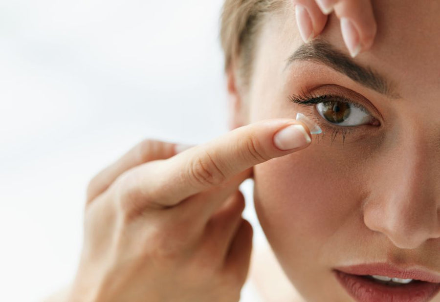 Person putting a contact lens in their eye with a white background