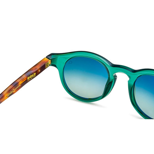 A close-up of a person's ear wearing earrings and striped sunglasses.