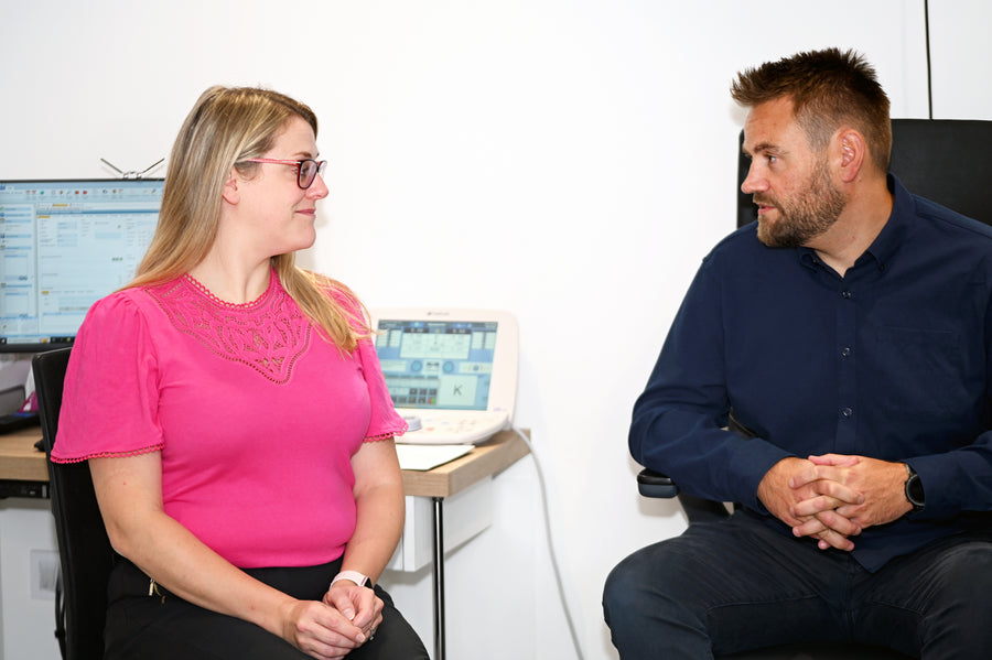 A person hikes through a snowy landscape with mountains in the background.