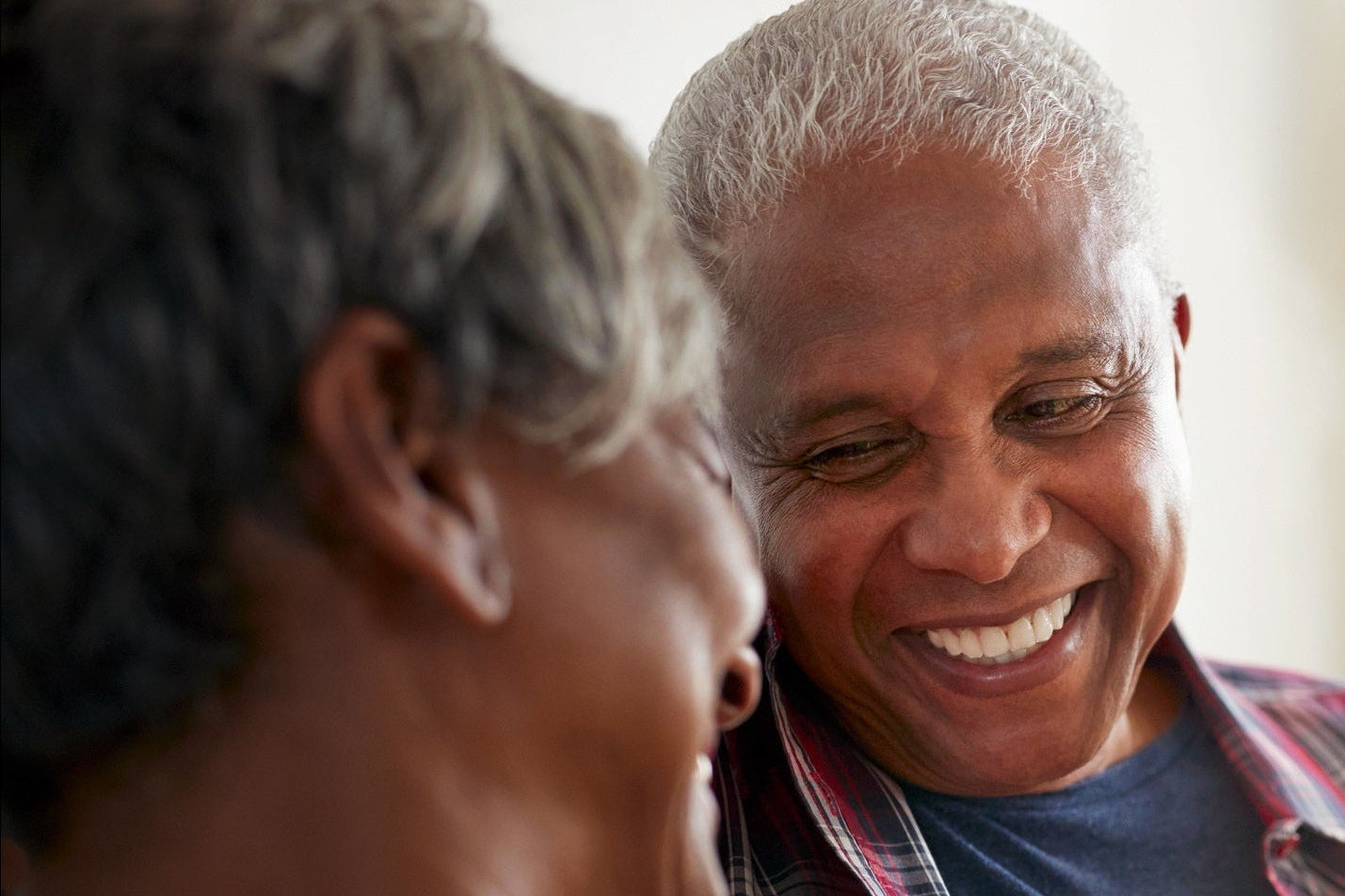 Two people sitting closely on a couch, sharing a warm moment with one holding a white coffee mug in a cozy living room.