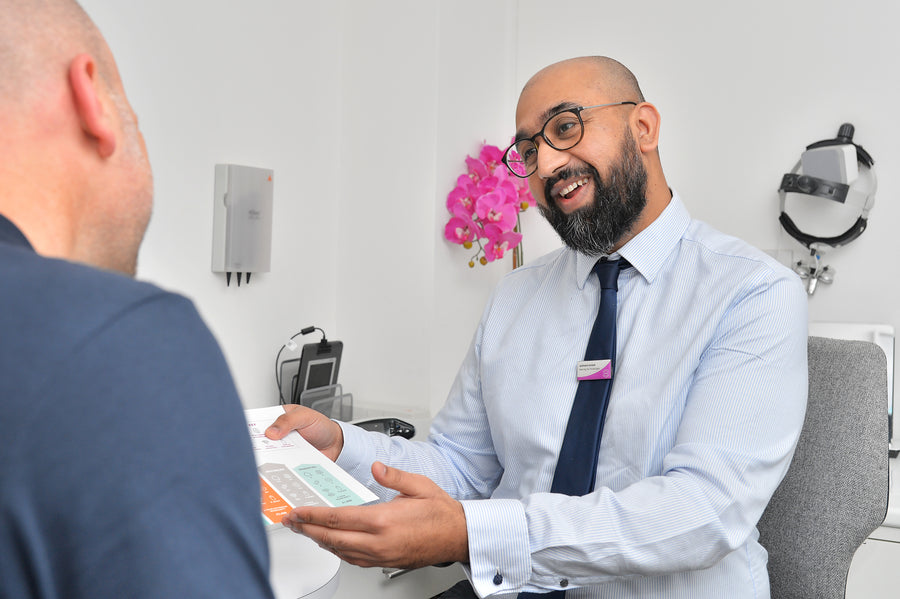 A white heated eye wand beside its teal and white packaging.