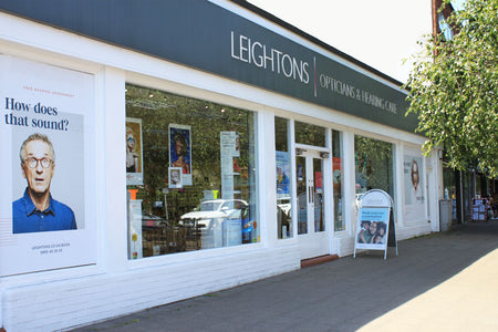 Leightons opticians and hearing care store exterior with promotional posters on the window.