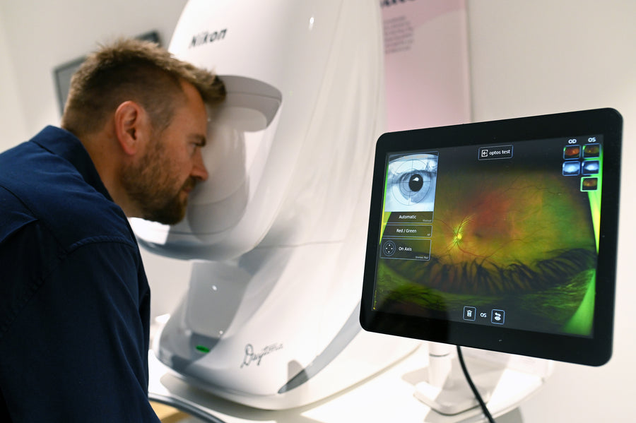 A woman smiles while holding a phone, surrounded by flowers.