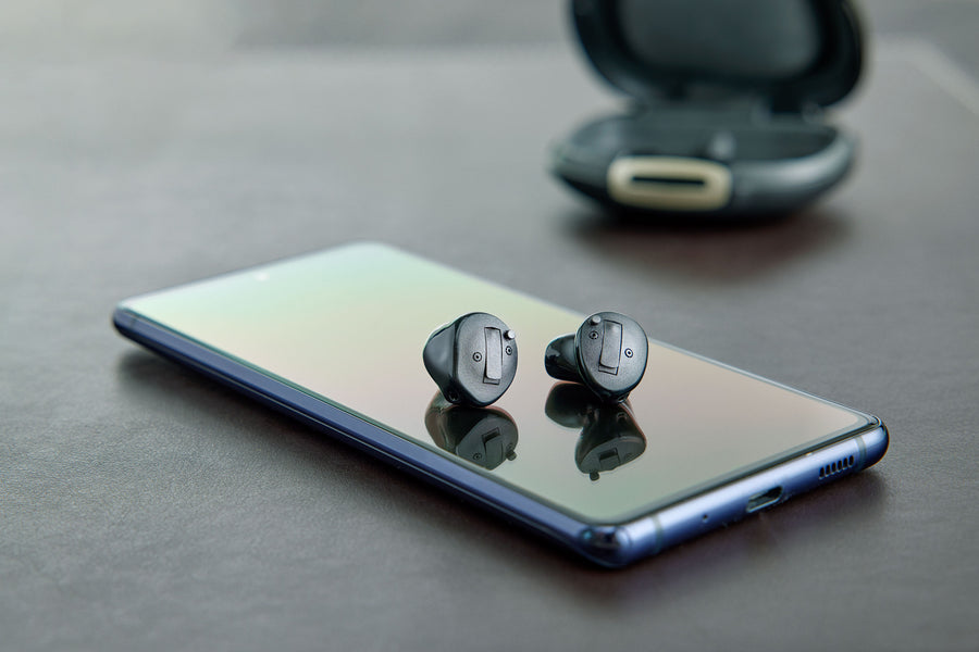 A man on a video call, holding a smartphone with a smiling woman.