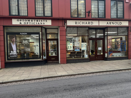 Optometrists and opticians shopfront with glass windows displaying products and advertisements.