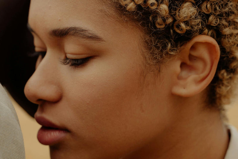 A sleek Oticon hearing aid with a clear ear mold attachment.