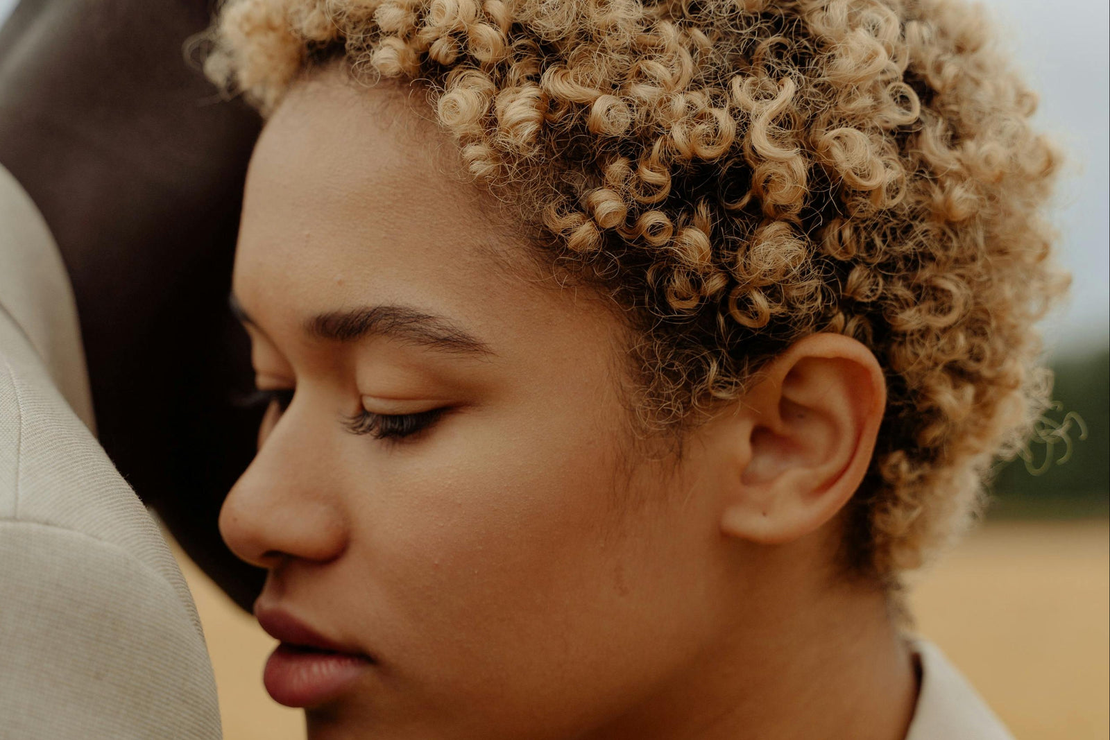 A sleek Oticon hearing aid with a transparent ear mold.