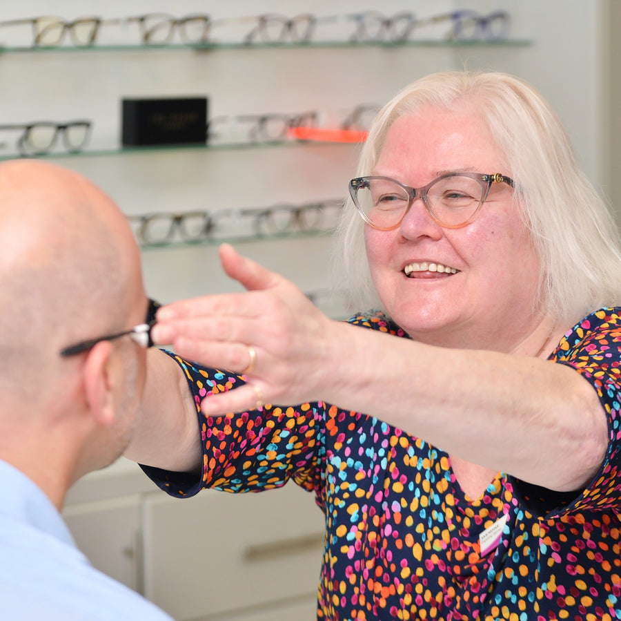 Person fitting glasses to a patient in a store setting.