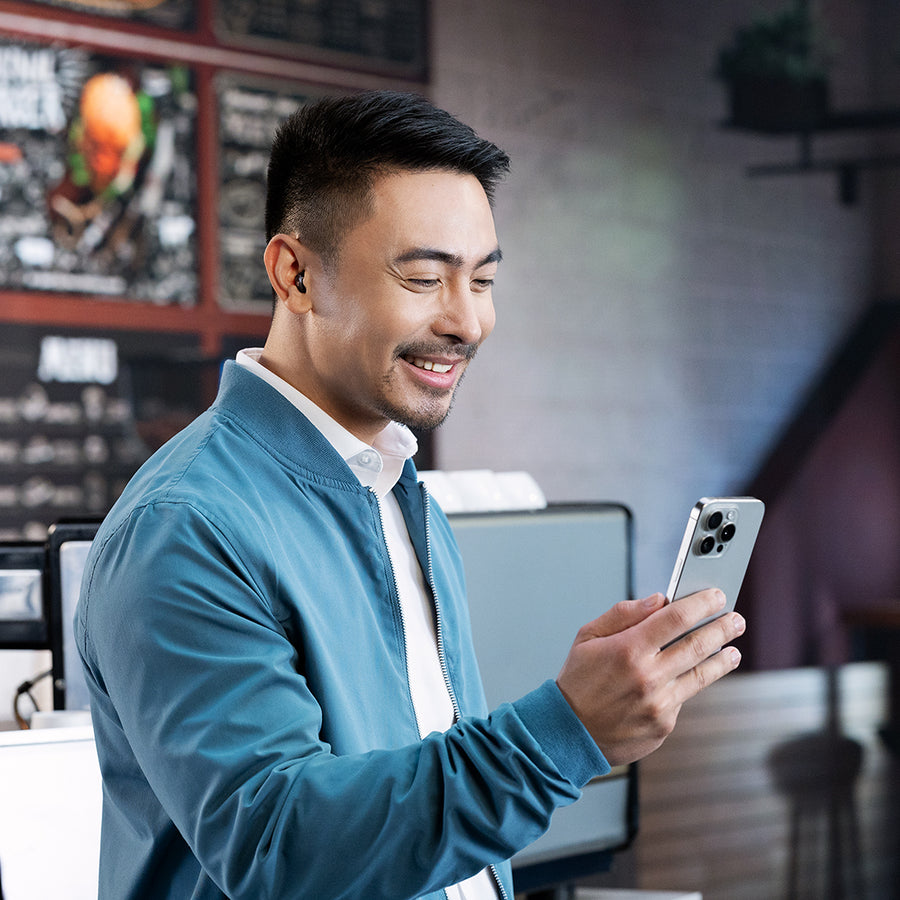 A smiling woman in an armchair with a brick wall behind her.